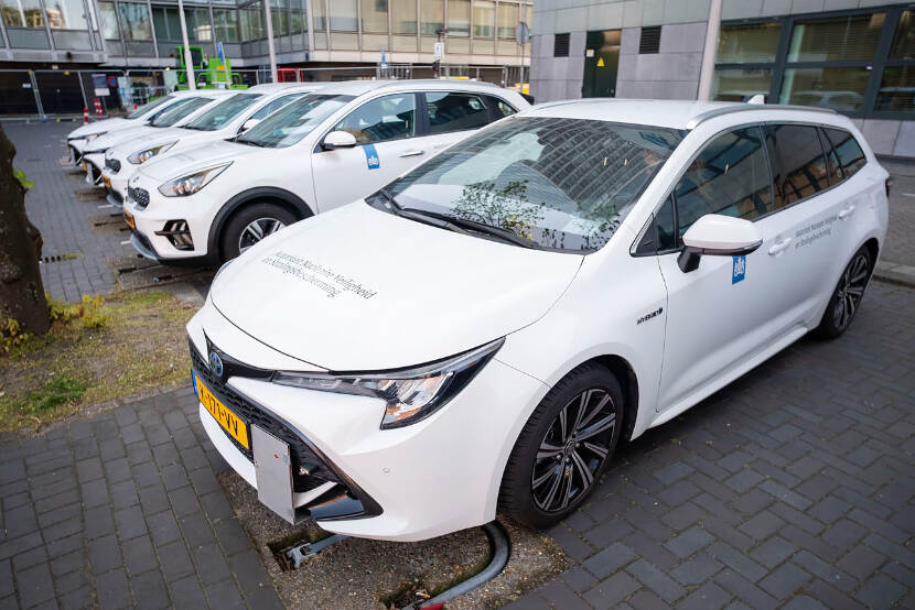 Een rij geparkeerde, witte ANVS-auto's. Op de zijkant en neus van de auto staat Autoriteit Nucleaire Veiligheid en Stralingsbescherming en het logo van de Rijksoverheid.